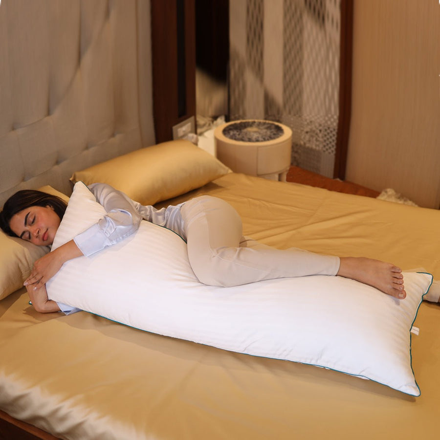 Woman sleeping on her side hugging a full-length Seevo body pillow on a gold satin bed