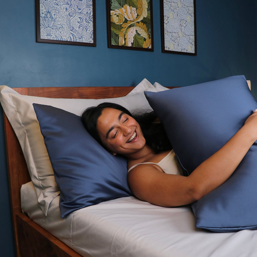 Woman relaxing in bed with blue Seevo satin pillow covers